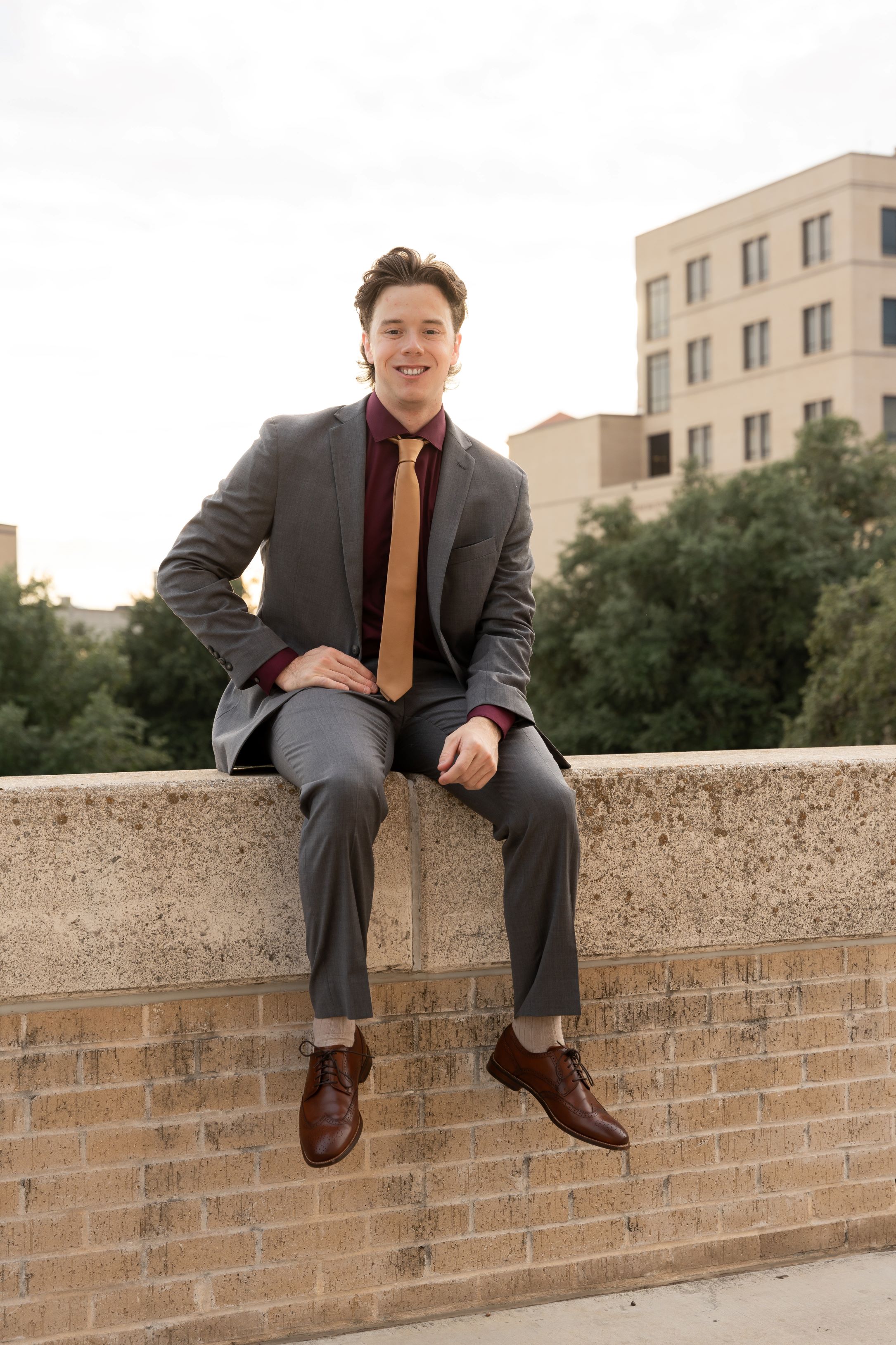 Jack Dressed in a suit and tie posing in a sitting position for graduation pictures