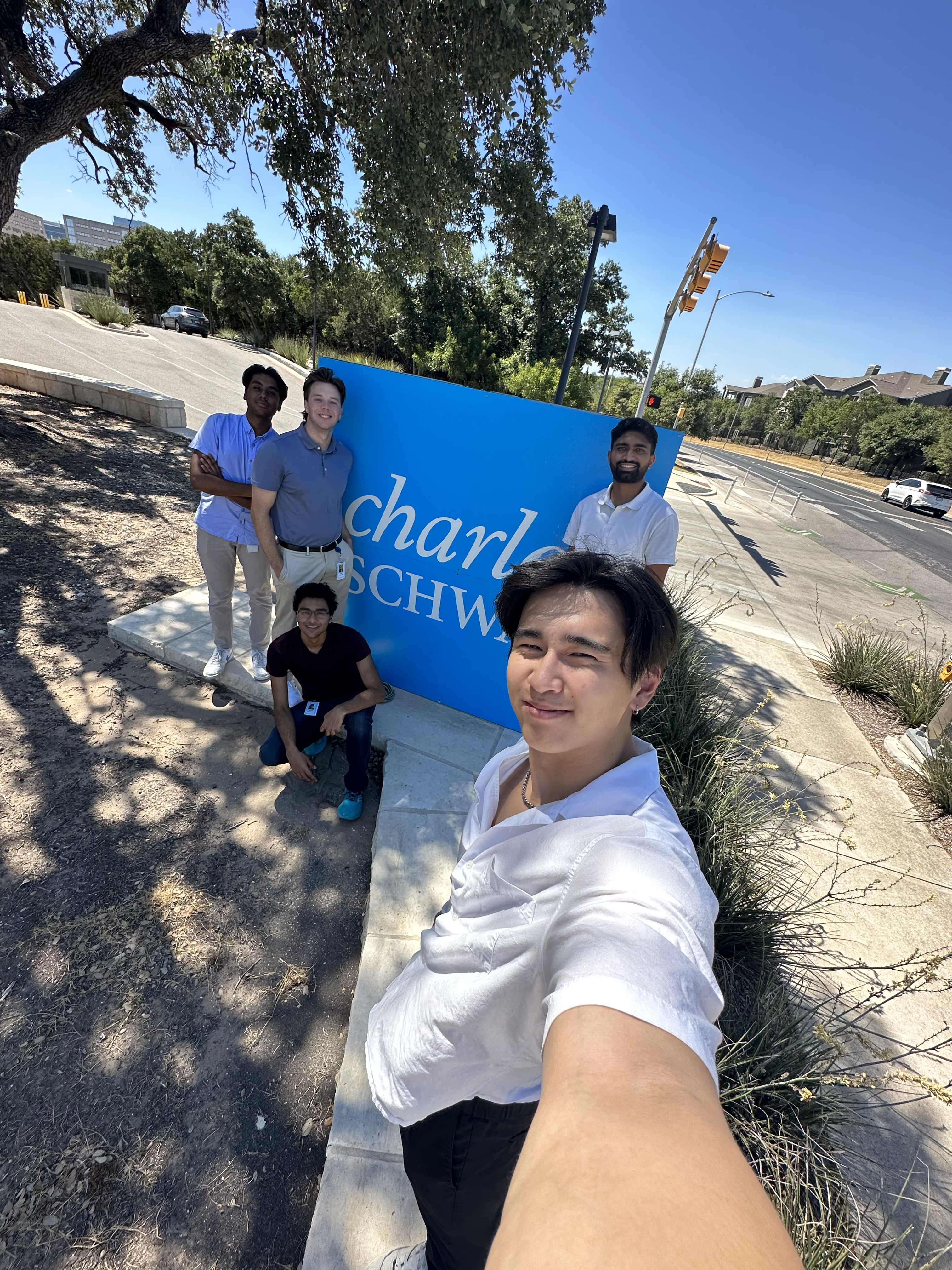 Jack and his fellow interns in front of the Charles Schwab Office sign